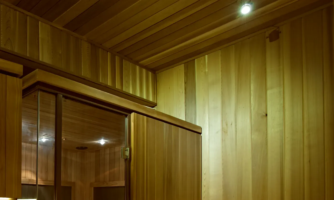 Cedar plank walls and ceiling in BRC's sauna corridor, lit by a single warm lamp.
