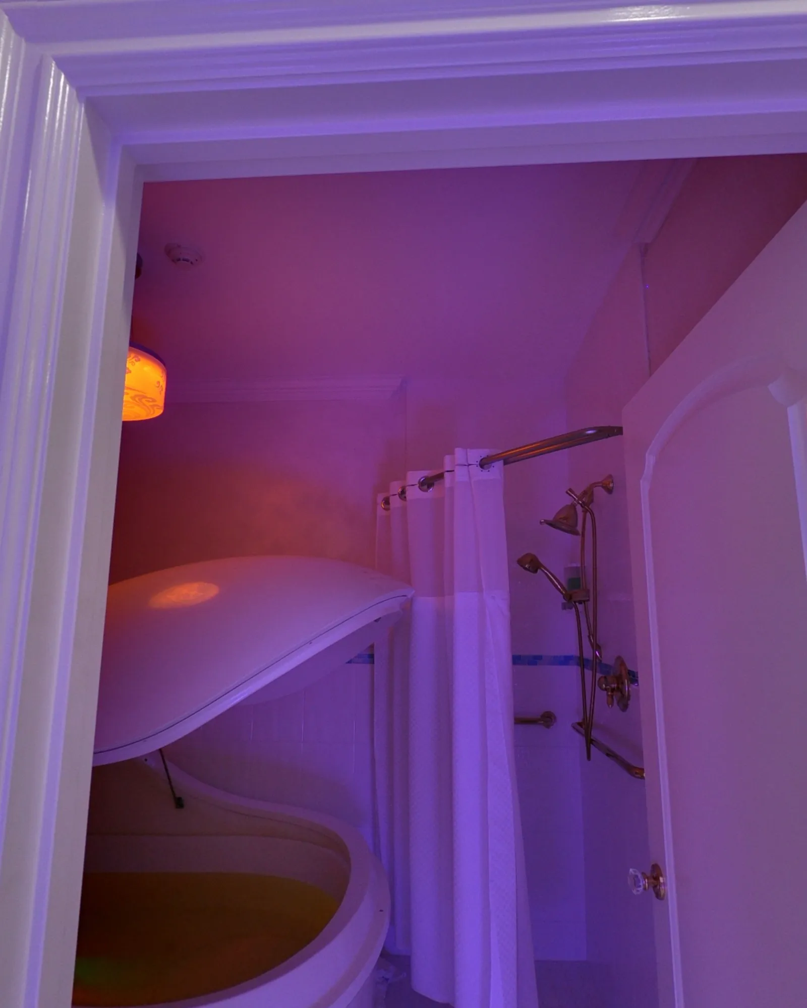 The float pod with its lid raised, in a violet-lit room beside a shower.