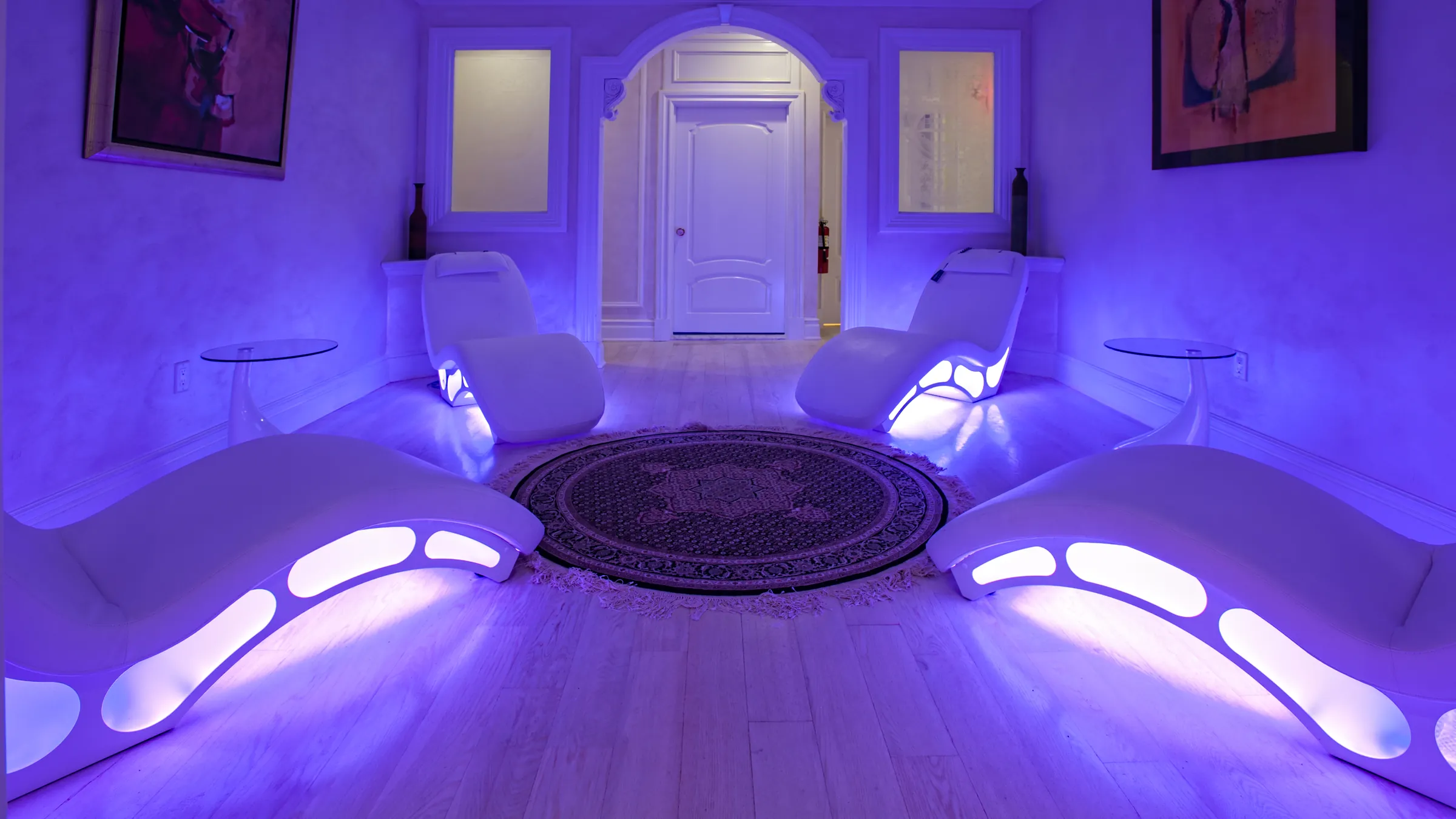 BRC's violet lounge: white loungers glowing on a round rug under an arched doorway.